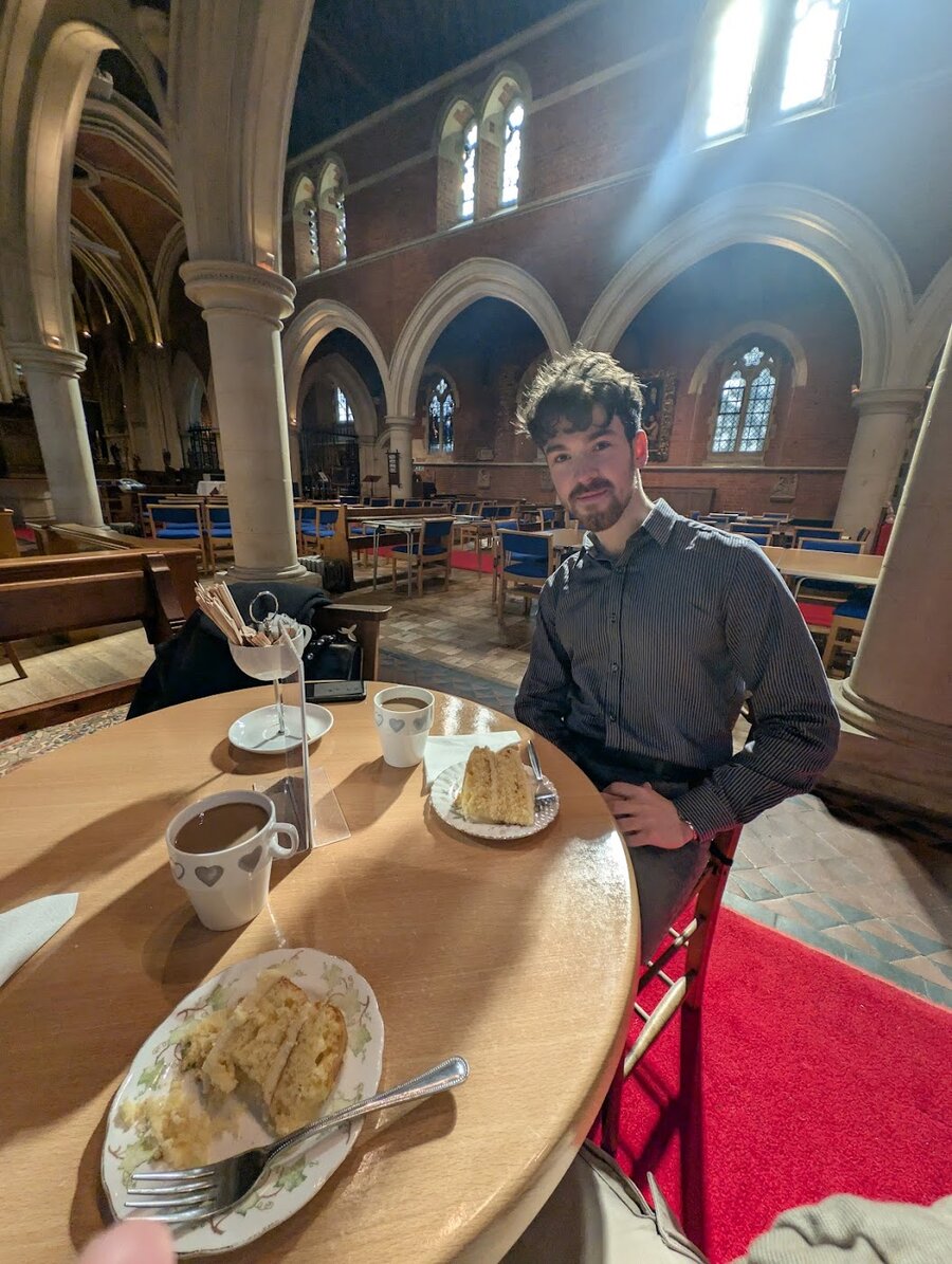 Jason at a church café table with cake and tea