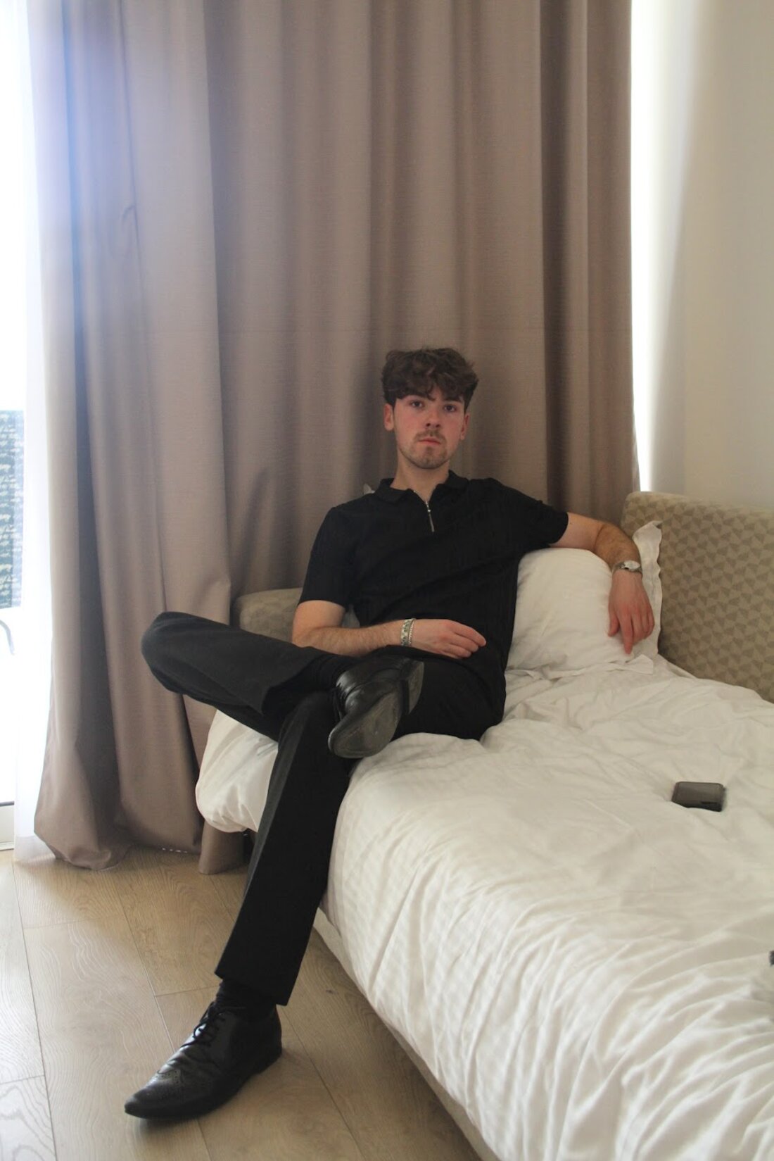 Jason Harding reclining in all black with dress shoes, photographed like a menswear editorial
